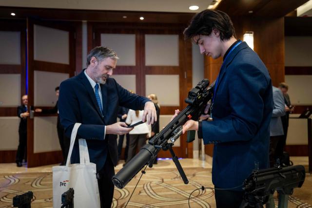 Participants inspect a weapon displayed at a stand during the second day of Warsaw Security Forum in Warsaw, Poland on October 13, 2026. (Photo by Wojtek RADWANSKI / AFP)