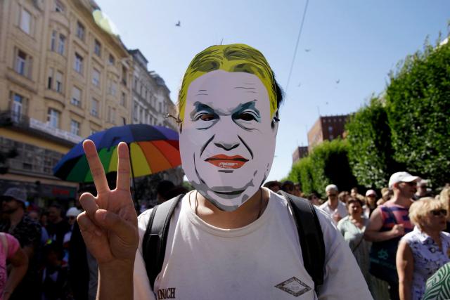 (FILES) A participant wearing a mask depicting then Hungary's Prime Minister Viktor Orban flashes the victory sign during the Budapest Pride march, on June 28, 2025 in Budapest, despite a governmental ban of the event. Hungarian lawmakers on October 13, 2026 voted to remove anti-LGBTQ provisions in a 2021 "child protection" law adopted under nationalist ex-leader Viktor Orban. Parliament passed a bill with 139 votes in favour and 51 votes against, marking the first significant reversal of Orban's curbs targeting the LGBTQ community since pro-EU Prime Minister Peter Magyar took power in May 2026. (Photo by Peter Kohalmi / AFP)