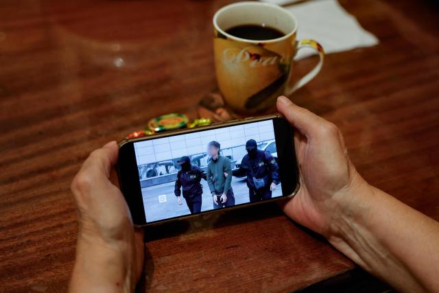 A person watches a news feed running a Russia's FSB security service footage of the operation to detain a Japanese journalist accused of espionage, on a smartphone in Moscow on October 13, 2026. Russia's FSB security service said on October 13, 2026 it had arrested a Japanese journalist on espionage charges, state media reported. Moscow accused the man -- a reporter with the Hokkaido Shimbun newspaper -- of working for Japanese intelligence to collect information about Russia's defensive capabilities on the Far East island of Sakhalin. (Photo by TATYANA MAKEYEVA / AFP)
