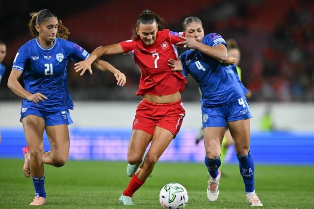 Israel's defender #21 Mia Shvill, Switzerland's midfielder #07 Riola Xhemaili and Israel's defender #04 Itaf Alkisi fight for the ball during the Women’s FIFA World Cup 2027 qualifyers play-off football match between Switzerland and Israel at Stade de Tourbillon in Sion, Switzerland, on October 13, 2026. (Photo by Fabrice COFFRINI / AFP)