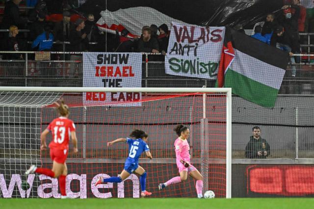 Pro-Palestinian demonstrators stage a protest in the stands during the Women’s FIFA World Cup 2027 qualifyers play-off football match between Switzerland and Israel at Stade de Tourbillon in Sion, Switzerland, on October 13, 2026. (Photo by Fabrice COFFRINI / AFP)