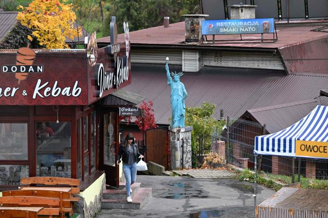 A woman leaves a kebab shop passing a replica of the Statue of Liberty next to the former restaurant 'Flavors of NATO' in Szczawnica, Lesser Poland Voivodeship on October 13, 2026. (Photo by Sergei GAPON / AFP)