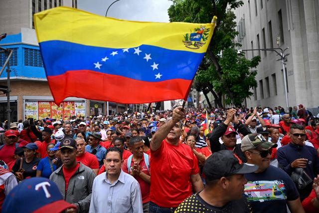 A supporter of Venezuela's government waves a Venezuelan flag during a march in support of the dialogue process between a sector of the opposition and the government, and to demand the lifting of sanctions against Venezuela, in Caracas on October 13, 2026. (Photo by Federico PARRA / AFP)