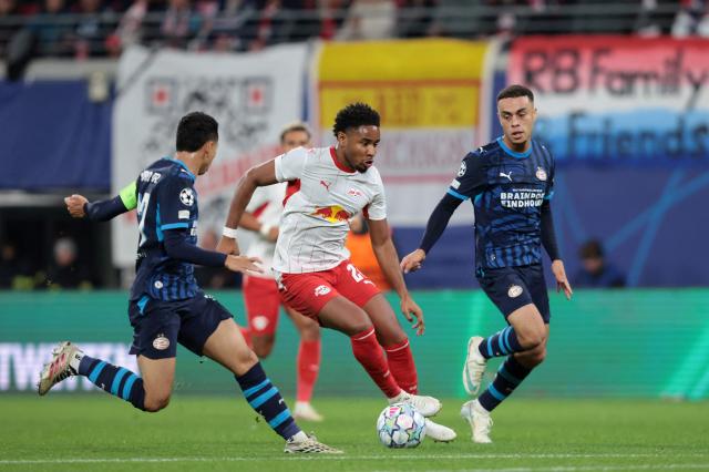 (From L) PSV Eindhoven's Brazilian defender #17 Mauro Junior, Leipzig's French forward #28 Christopher Nkunku and PSV Eindhoven's US defender #08 Sergino Dest vie for the ball during the UEFA Champions League football match between RB Leipzig and PSV Eindhoven in Leipzig, eastern Germany on October 13, 2026. (Photo by Ronny HARTMANN / AFP)