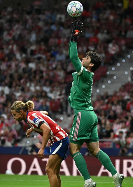 Manchester United's Belgian goalkeeper #01 Senne Lammens catches the ball next to Atletico Madrid's Spanish midfielder #14 Marcos Llorente during the UEFA Champions League, league phase, matchday 2, football match between Club Atletico de Madrid and Manchester United at the Metropolitano stadium in Madrid on October 13, 2026. (Photo by Javier SORIANO / AFP)
