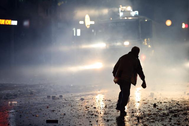 A protester holds a stone during clashes with riot police in Skanderbeg square during a protest in Tirana on October 13, 2026, as hundreds rallied to demand the resignation of Albanian Prime Minister Edi Rama and better education. Police used tear gas and water cannons as protesters threw stones, smashed windows at the education ministry, tore down a fence and set rubbish bins on fire, with six police officers and a female journalist injured, according to police. (Photo by Adnan Beci / AFP)