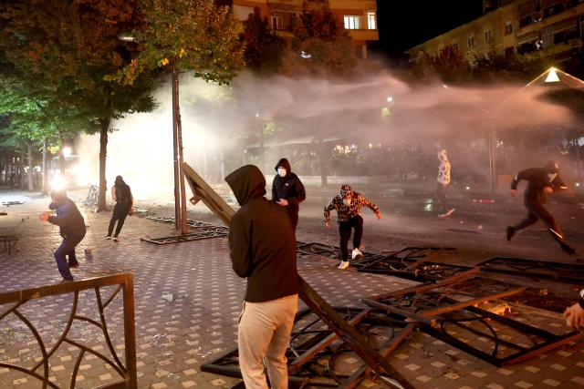 Protesters clash with riot police in Skanderbeg square during a protest in Tirana on October 13, 2026, as hundreds rallied to demand the resignation of Albanian Prime Minister Edi Rama and better education. Police used tear gas and water cannons as protesters threw stones, smashed windows at the education ministry, tore down a fence and set rubbish bins on fire, with six police officers and a female journalist injured, according to police. (Photo by Adnan Beci / AFP)