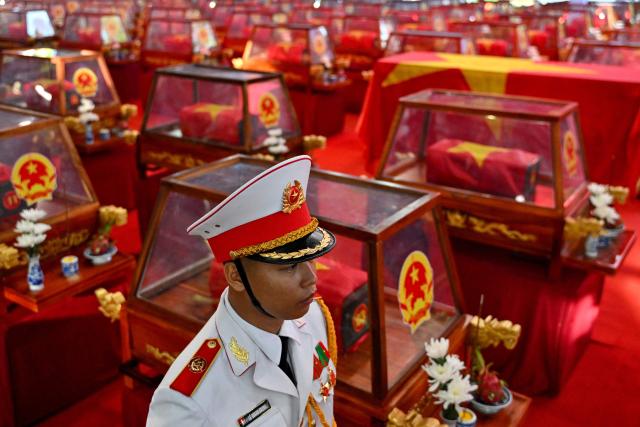 TOPSHOT - A soldier stands beside caskets containing the remains of fallen soldiers at Le Thi Rieng Park in Ho Chi Minh City on October 14, 2026. Vietnam held funeral rites for more than 700 of its war dead on October 14, unearthed in a major push to identify those missing from decades of conflict with France and the United States. (Photo by Nhac NGUYEN / AFP)