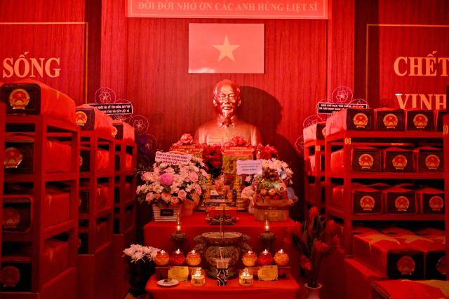 A memorial altar with the bust of Vietnam's late revolutionary leader Ho Chi Minh is seen with caskets containing the remains of fallen soldiers inside a holding room at Le Thi Rieng Park in Ho Chi Minh City on October 13, 2026. Vietnam held funeral rites for more than 700 of its war dead on October 14, unearthed in a major push to identify those missing from decades of conflict with France and the United States. (Photo by Nhac NGUYEN / AFP)
