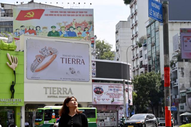 This photo taken on October 3, 2026 shows Le Ngoc Mai Uyen standing besude street signage bearing the name of her late grandmother and revolutionary fighter Le Thi Rieng, in Ho Chi Minh City. Vietnam held funeral rites for more than 700 of its war dead on October 14, unearthed in a major push to identify those missing from decades of conflict with France and the United States. (Photo by Nhac NGUYEN / AFP)