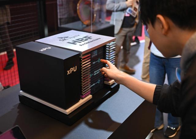 Visitors look at a model of SK hynix's High Bandwidth Flash (HBF), a next-generation storage technology, during a semiconductor exhibition at the COEX convention and exhibition centre in Seoul on October 14, 2026. (Photo by Jung Yeon-je / AFP)
