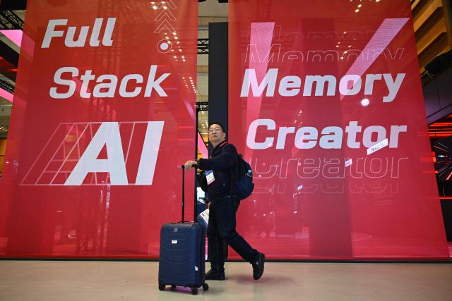 A man walks past banners reading "Full stack AI memory creator" at the SK hynix booth during a semiconductor exhibition at the COEX convention and exhibition centre in Seoul on October 14, 2026. (Photo by Jung Yeon-je / AFP)