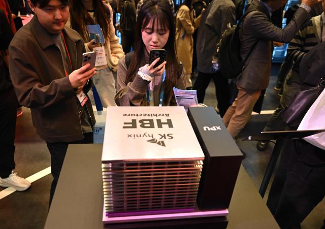 Visitors look at a model of SK hynix's High Bandwidth Flash (HBF), a next-generation storage technology, during a semiconductor exhibition at the COEX convention and exhibition centre in Seoul on October 14, 2026. (Photo by Jung Yeon-je / AFP)