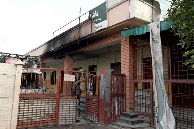 Security personnel inspect burnt vehicles at the National Database and Registration Authority (NADRA) office following clashes, in Bara on the outskirts of Peshawar on October 14, 2026. (Photo by Abdul MAJEED / AFP)
