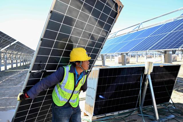 A worker installs solar panels at the Longi Yongning 400-megawatt photovoltaic project site on the Gobi Desert at the eastern foothills of the Helan Mountains in Yinchuan, in northwestern China's Ningxia Hui Autonomous Region, on October 13, 2026. (Photo by CN-STR / AFP) / China OUT