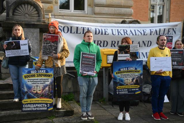 Protesters hold signs ahead the beginning of the trial against Ukrainian national Serhii K, a former army officer accused of the Nord Stream gas pipeline bombing around four years ago, at the Higher Regional Court in Hamburg, northern Germany on October 14, 2026. According to the indictment filed by the Federal Public Prosecutors Office, Serhii K, who was arrested last year while on vacation in Italy, is alleged to have planned the act together with other members of the Ukrainian military. In addition, the defendant is said to have led the team that blew up the natural gas pipelines under the Baltic Sea at the end of September 2022. The pipelines were used to transport Russian natural gas to Germany. According to the indictment, the attack was carried out on behalf of Ukrainian state authorities; the background was the Russian war of aggression against Ukraine, which began in early 2022. The Ukrainian government denies any official involvement. (Photo by Gregor Fischer / AFP)