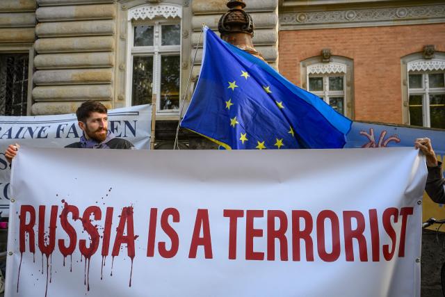 Pro Ukrainian protestors holds a banner reading, Russia is a terrorist" outside the Higher Regional Court in Hamburg, northern Germany on October 14, 2026, prior to the cort case against defendant Serhii K, a former Ukrainian army officer over the Nord Stream gas pipeline bombing. According to the indictment filed by the Federal Public Prosecutors Office, Serhii K, who was arrested last year while on vacation in Italy, is alleged to have planned the act together with other members of the Ukrainian military. In addition, the defendant is said to have led the team that blew up the natural gas pipelines under the Baltic Sea at the end of September 2022. The pipelines were used to transport Russian natural gas to Germany. According to the indictment, the attack was carried out on behalf of Ukrainian state authorities; the background was the Russian war of aggression against Ukraine, which began in early 2022. The Ukrainian government denies any official involvement. (Photo by Gregor Fischer / AFP)