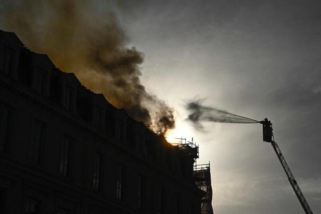 A firefighter tries to extinguish a fire burning on the roof of the Gare d'Austerlitz railway station in Paris on October 14, 2026. (Photo by JULIEN DE ROSA / AFP)