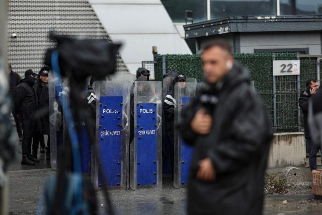 Turkish anti-riot police officers stand at the bottom of the building during a police raid at the headquarters of pro-opposition Halk TV in Istanbul, on October 14, 2026. The head of Turkey's pro-opposition Halk TV lashed out after police raided the channel's headquarters, halting live broadcasts and arresting 11 in a move against the country's most watched news channel. (Photo by BERK OZKAN / AFP)