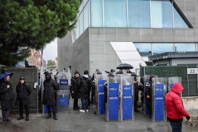Turkish anti-riot police officers stand at the bottom of the building during a police raid at the headquarters of pro-opposition Halk TV in Istanbul, on October 14, 2026. The head of Turkey's pro-opposition Halk TV lashed out after police raided the channel's headquarters, halting live broadcasts and arresting 11 in a move against the country's most watched news channel. (Photo by BERK OZKAN / AFP)