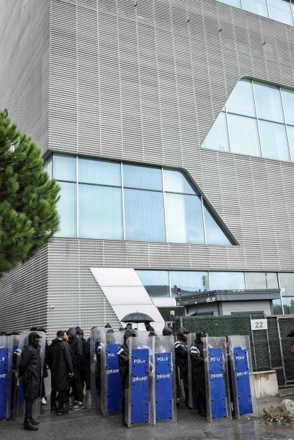 Turkish anti-riot police officers stand at the bottom of the building during a police raid at the headquarters of pro-opposition Halk TV in Istanbul, on October 14, 2026. The head of Turkey's pro-opposition Halk TV lashed out after police raided the channel's headquarters, halting live broadcasts and arresting 11 in a move against the country's most watched news channel. (Photo by BERK OZKAN / AFP)