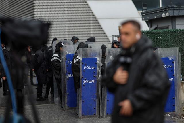 Turkish anti-riot police officers stand at the bottom of the building during a police raid at the headquarters of pro-opposition Halk TV in Istanbul, on October 14, 2026. The head of Turkey's pro-opposition Halk TV lashed out after police raided the channel's headquarters, halting live broadcasts and arresting 11 in a move against the country's most watched news channel. (Photo by BERK OZKAN / AFP)