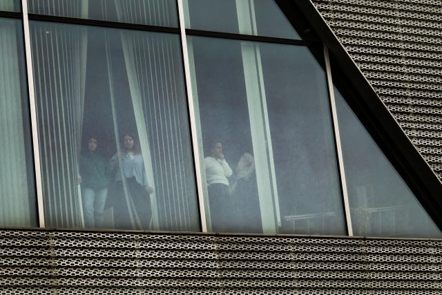 Employees watch from the windows during a police raid at the headquarters of pro-opposition Halk TV in Istanbul, on October 14, 2026. The head of Turkey's pro-opposition Halk TV lashed out after police raided the channel's headquarters, halting live broadcasts and arresting 11 in a move against the country's most watched news channel. (Photo by BERK OZKAN / AFP)