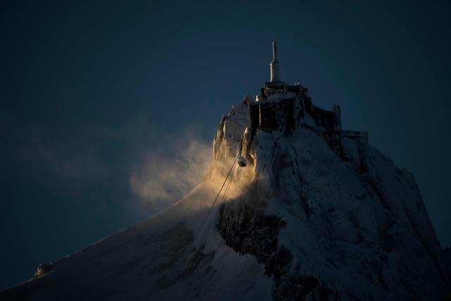(FILES) This photograph shows the cable car of L'aiguille du Midi of the Massif du Mont-Blanc mountain range in the French Alps, near Chamonix on February 13, 2026. Mont Blanc, the highest peak in Western Europe in the Alps, was measured in September 2026 at 4,807.47 meters—1.88 meters higher than the previous measurement reported in 2023—French surveyors announced on October 14, 2026. (Photo by OLIVIER CHASSIGNOLE / AFP)