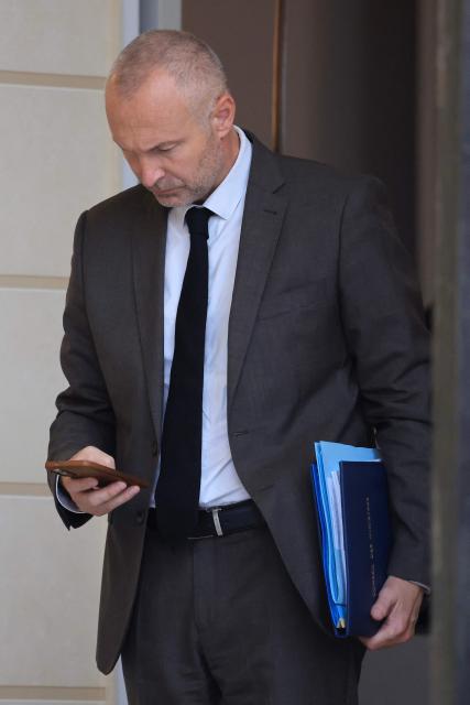 France's junior Minister in charge of parliament relations Laurent Panifous looks at his smartphone as he leaves the presidential Elysee Palace following the weekly Cabinet meeting in Paris on October 14, 2026. (Photo by Ludovic MARIN / AFP)