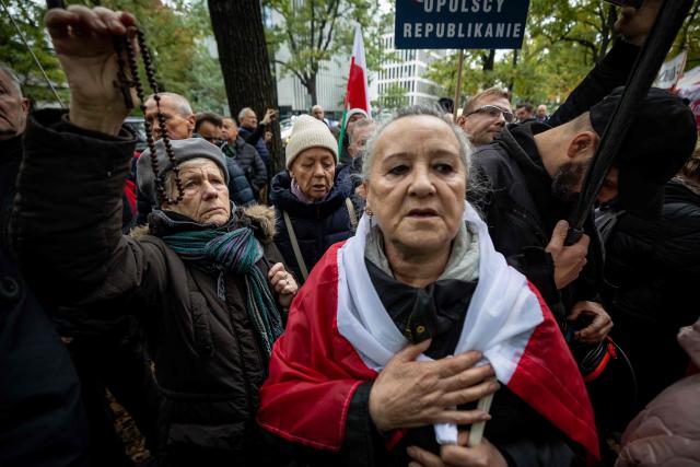 Anti-government protestors pray as they attend a demonstration in front of the Constitutional Court, Poland's highest court, in Warsaw on October 14, 2026. Right-wing protestors clashed with police in front of Poland's highest court on October 14, attempting to block its judges from entering the building and defending its overhaul by the previous government. (Photo by Wojtek RADWANSKI / AFP)