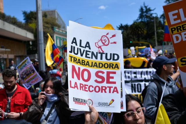 A demonstrator holds a placard reading "The Working Youth Will Not Be Cut Back" during a protest against the government of Colombian President Abelardo de la Espriella in Bogota on October 14, 2026, as part of a nationwide day of demonstrations called by labor unions, teachers' organizations, student groups and opposition sectors. (Photo by Sebastian BARROS / AFP)