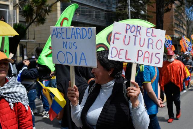 A demonstrator holds placards reading "Abelardo Hates Us" and "For the Future of the Country" during a protest against the government of Colombian President Abelardo de la Espriella in Bogota on October 14, 2026, as part of a nationwide day of demonstrations called by labor unions, teachers' organizations, student groups and opposition sectors. (Photo by Sebastian BARROS / AFP)