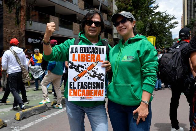 Demonstrators pose with a placard reading "Education Liberates, Fascism Enslaves" during a protest against the government of Colombian President Abelardo de la Espriella in Bogota on October 14, 2026, as part of a nationwide day of demonstrations called by labor unions, teachers' organizations, student groups and opposition sectors. (Photo by Sebastian BARROS / AFP)