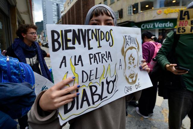 A demonstrator holds a placard reading "Welcome to the homeland of the devil" during a protest against the government of Colombian President Abelardo de la Espriella in Bogota on October 14, 2026, during a nationwide day of demonstrations called by labor unions, teachers' organizations, student groups and opposition sectors. (Photo by Sebastian BARROS / AFP)