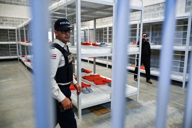 A police officer stands guard at the High-Security Center for the Containment of Organized Crime (CACCO) during its inauguration in Alajuela, Costa Rica, on October 14, 2026. The mega-prison is modeled after El Salvador's maximum-security CECOT facility as part of Costa Rica's efforts to strengthen its response to organized crime. (Photo by Ezequiel BECERRA / AFP)