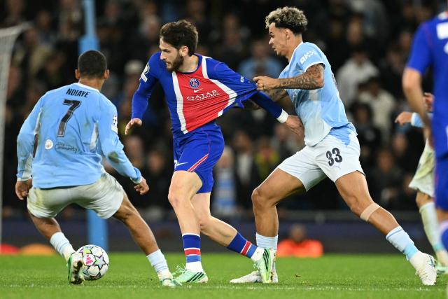 Paris Saint-Germain's Georgian midfielder #07 Khvicha Kvaratskhelia (C) held back by Manchester City's English midfielder #33 Nico O'Reilly (R) during the UEFA Champions League, league phase football match between Manchester City and Paris Saint Germain at the Etihad Stadium in Manchester, north west England, on October 14, 2026. (Photo by Oli SCARFF / AFP)