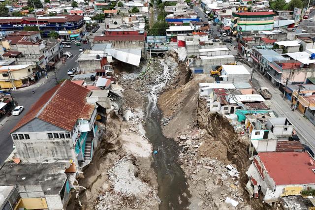 Aerial view showing damages through the passage of the Pinula River triggering severe erosion and the collapse of homes after a heavy rains  in the Villa Hermosa I neighborhood of San Miguel Petapa, Guatemala, on October 14, 2026. Authorities report that the current rainy season has left 22 people dead, 44 injured and more than 212,000 affected, while causing extensive damage to infrastructure, including some 13,000 homes, 660 roads, 37 bridges and 52 schools. (Photo by Johan ORDÓÑEZ / AFP)