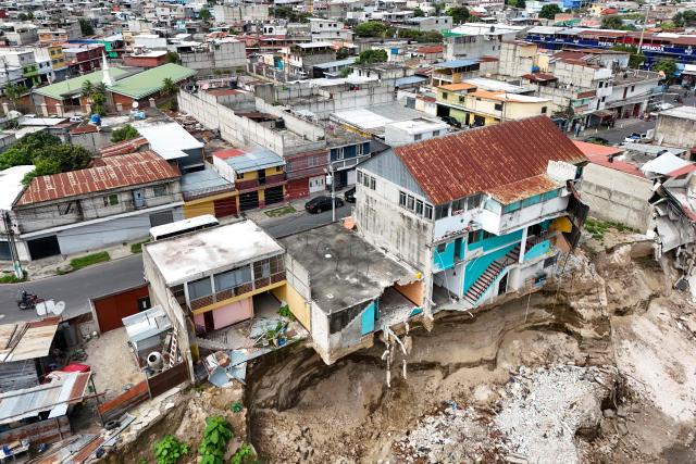 Aerial view showing damages through the passage of the Pinula River triggering severe erosion and the collapse of homes after a heavy rains  in the Villa Hermosa I neighborhood of San Miguel Petapa, Guatemala, on October 14, 2026. Authorities report that the current rainy season has left 22 people dead, 44 injured and more than 212,000 affected, while causing extensive damage to infrastructure, including some 13,000 homes, 660 roads, 37 bridges and 52 schools. (Photo by Johan ORDÓÑEZ / AFP)