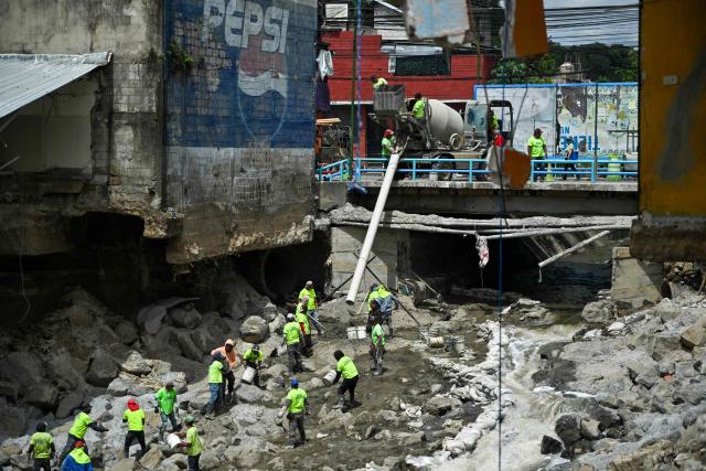 Municipal workers work next to damage caused by the Pinula River, which triggered severe erosion and the collapse of homes following heavy rains in the Villa Hermosa I neighborhood of San Miguel Petapa, Guatemala, on October 14, 2026. Authorities report that the current rainy season has left 22 people dead, 44 injured and more than 212,000 affected, while causing extensive damage to infrastructure, including some 13,000 homes, 660 roads, 37 bridges and 52 schools. (Photo by Johan ORDONEZ / AFP)