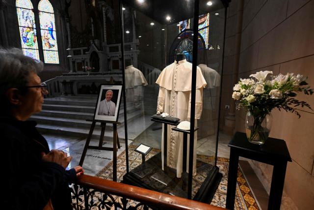 A woman looks at a cassock of late Pope Francis at the Basilica of Our Lady of Lujan in Lujan, Buenos Aires Province, Argentina on October 14, 2026. (Photo by Luis ROBAYO / AFP)