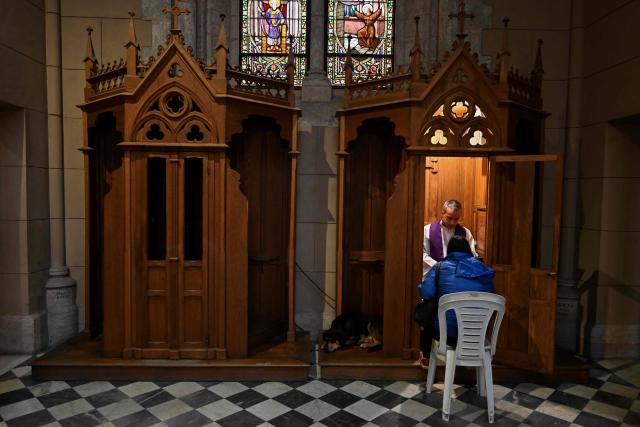 A priest hears the confession of a Catholic woman at the Basilica of Our Lady of Lujan in Lujan, Buenos Aires Province, Argentina on October 14, 2026. (Photo by Luis ROBAYO / AFP)