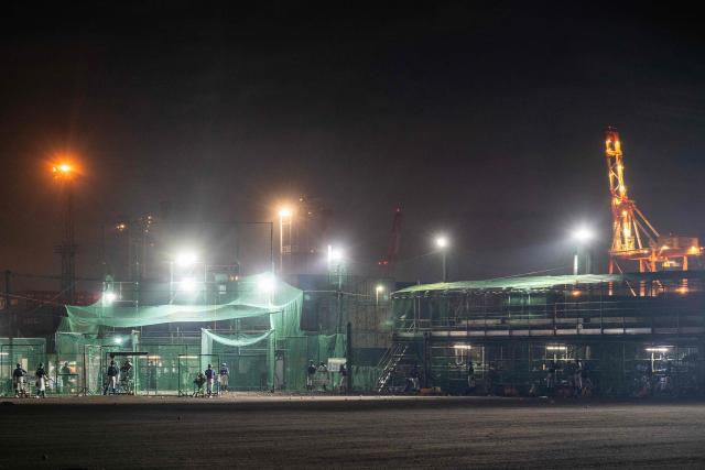 A baseball team practices batting in the nets next to the Yokohama port in Yokohama on October 14, 2026. (Photo by Andrew Caballero-Reynolds / AFP)