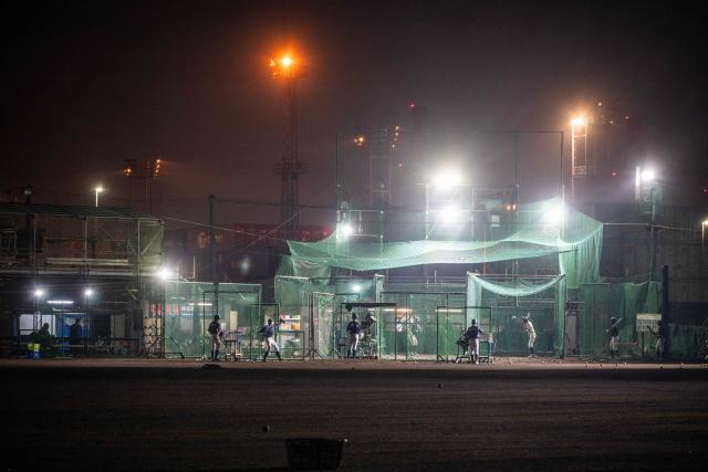 A baseball team practices batting in the nets next to the Yokohama port in Yokohama on October 14, 2026. (Photo by Andrew Caballero-Reynolds / AFP)