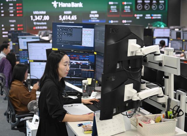 Currency dealers watch monitors as an electronic screen shows South Korea's benchmark stock index (KOSPI) in a foreign exchange dealing room at the Hana Bank headquarters in Seoul on October 15, 2026. Japan's benchmark stock index lost more than three percent on October 15, and South Korean shares shed six percent, after Wall Street ended lower following a hotter-than-expected US inflation reading. (Photo by Jung Yeon-je / AFP)
