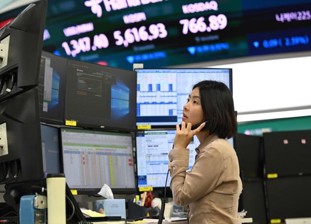 Currency dealers watch monitors as an electronic screen shows South Korea's benchmark stock index (KOSPI) in a foreign exchange dealing room at the Hana Bank headquarters in Seoul on October 15, 2026. Japan's benchmark stock index lost more than three percent on October 15, and South Korean shares shed six percent, after Wall Street ended lower following a hotter-than-expected US inflation reading. (Photo by Jung Yeon-je / AFP)