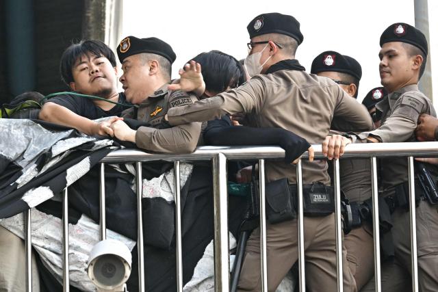 Police try to stop demonstrators from displaying a banner during a protest against the International Monetary Fund (IMF) and World Bank Group in Bangkok on October 15, 2026, as the IMF Annual Meetings take place in the Thai capital. (Photo by ANTHONY WALLACE / AFP)