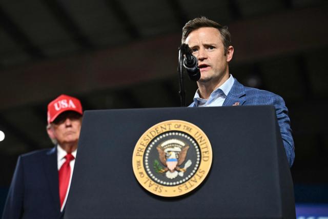 Republican candidate for US Congress Aaron Flint speaks while US President Donald Trump looks on during a campaign rally at the Majestic Valley Arena in Kalispell, Montana on October 14, 2026. President Trump is campaigning for Flint. (Photo by Kent NISHIMURA / AFP)