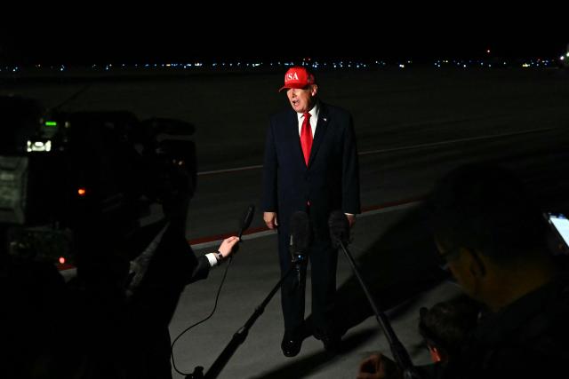 US President Donald Trump speaks with pool reporters during a stop over to switch planes at Missoula Montana Airport, in Missoula, Montana on October 14, 2026. President Trump is returning to Washington, DC after speaking at campaign rallies in Alaska, Arizona and Montana. (Photo by Kent NISHIMURA / AFP)
