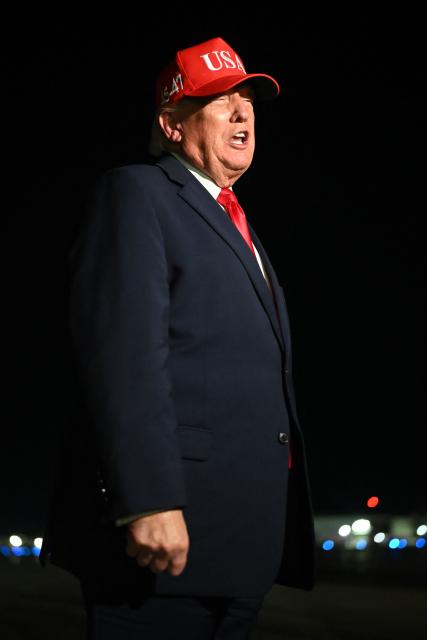 US President Donald Trump speaks with pool reporters during a stop over to switch planes at Missoula Montana Airport, in Missoula, Montana on October 14, 2026. President Trump is returning to Washington, DC after speaking at campaign rallies in Alaska, Arizona and Montana. (Photo by Kent NISHIMURA / AFP)