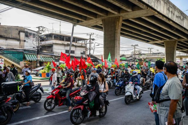 Commuters drive past demonstrators taking part in a protest against the International Monetary Fund (IMF) and World Bank Group in Bangkok on October 15, 2026, as the IMF Annual Meetings take place in the Thai capital. (Photo by ANTHONY WALLACE / AFP)